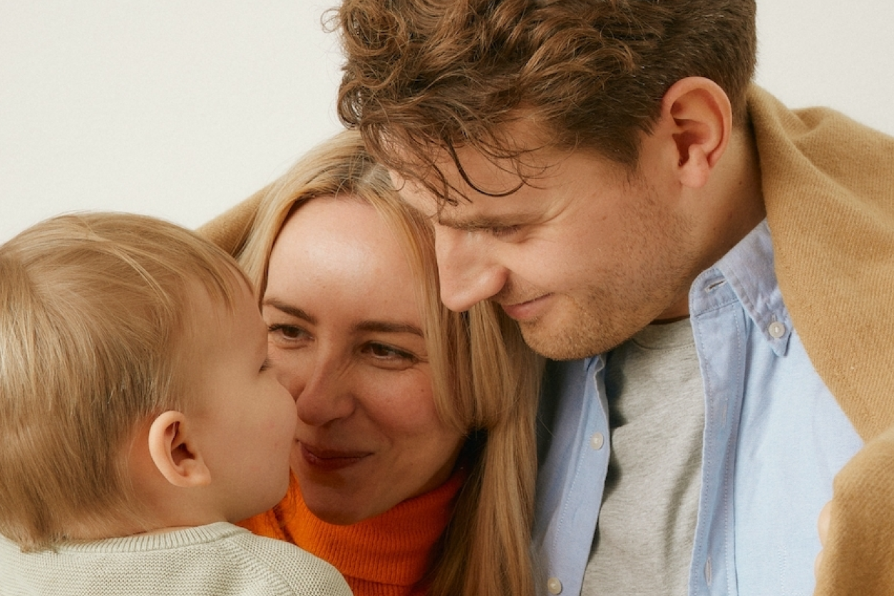 two parents looking at a young child with admiration