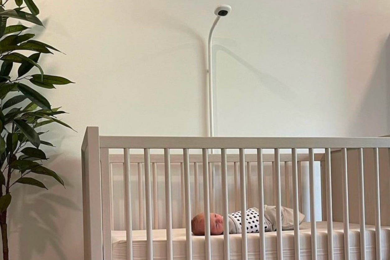 newborn baby in crib under Nanit monitor
