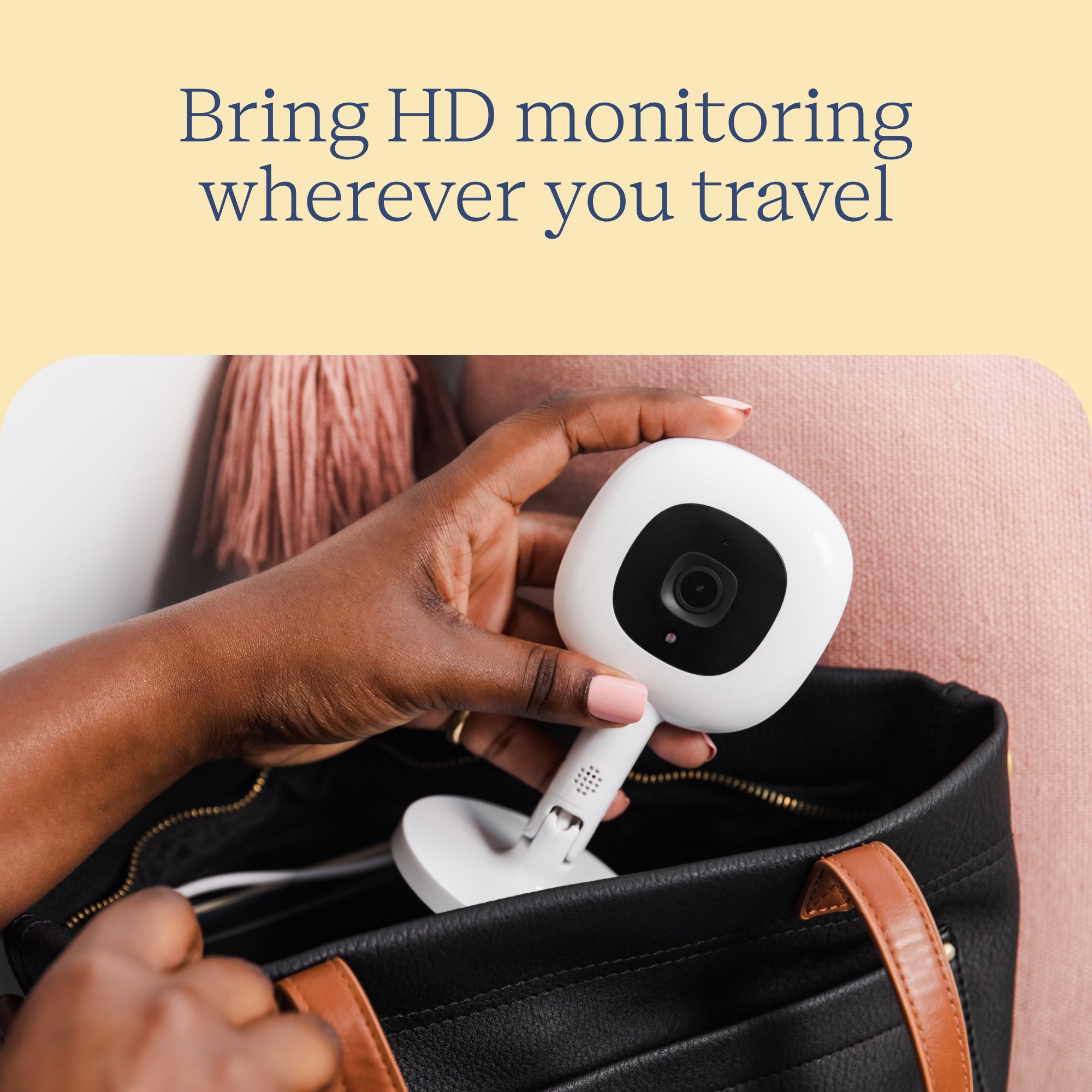 Hand holding a small white camera with text 'Bring HD monitoring wherever you travel' on a beige background