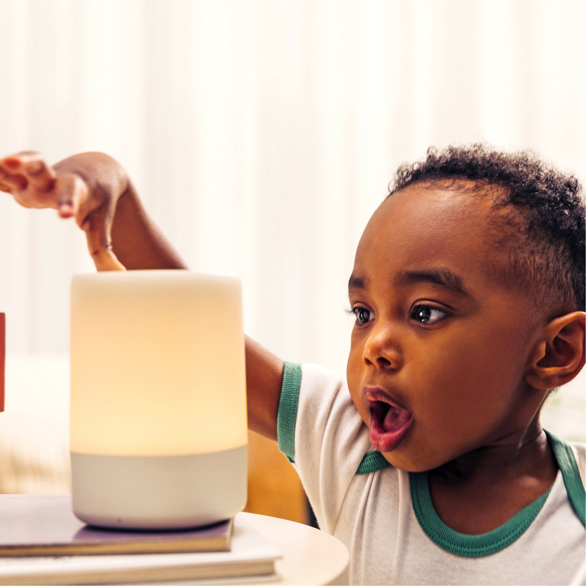 baby looking at glo sound machine with surprise and touching it
