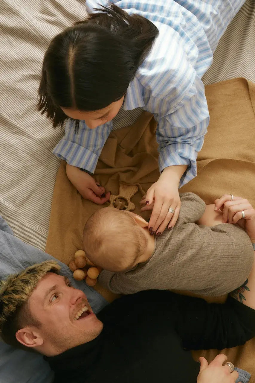 woman and man laying on a bed playing with baby