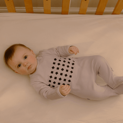 baby laying in crib in lilac pajamas