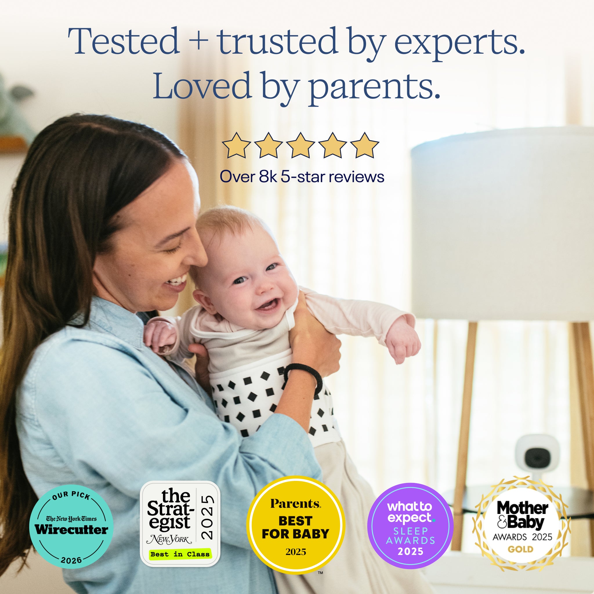 Woman holding a baby with product awards displayed on a blurred background