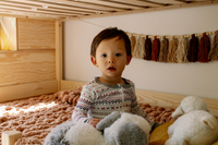 child wearing Nanit 2-Piece Sleep Wear Holiday Pajamas in fair isle