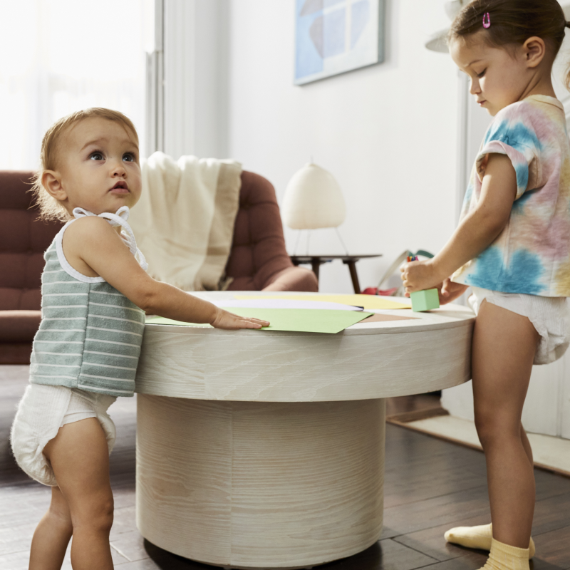 One baby and one toddler both wearing Coterie Diaper