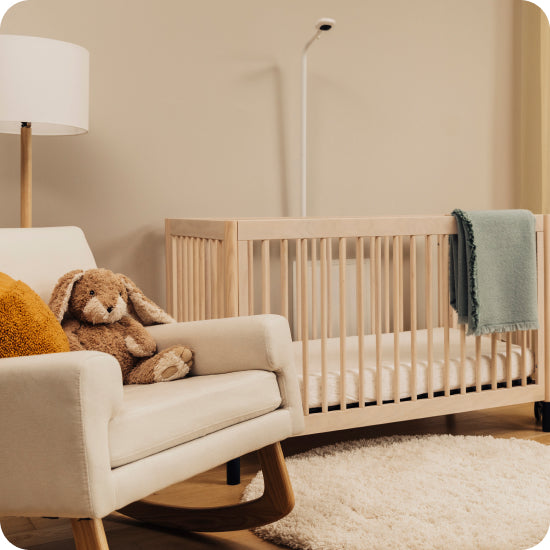 Nursery with wooden crib, plush toys, and a lamp in a warm-toned room.