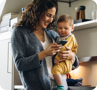 Mom holding baby while looking at her mobile