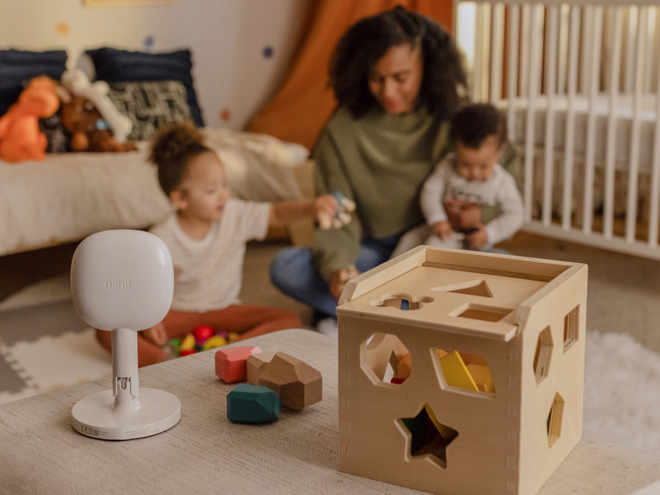 mom playing with kids while nanit baby monitor + flex stand monitors with blocks next to it