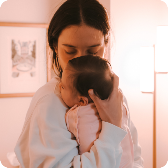 mom gently holds baby close to their chest in a warm indoor setting