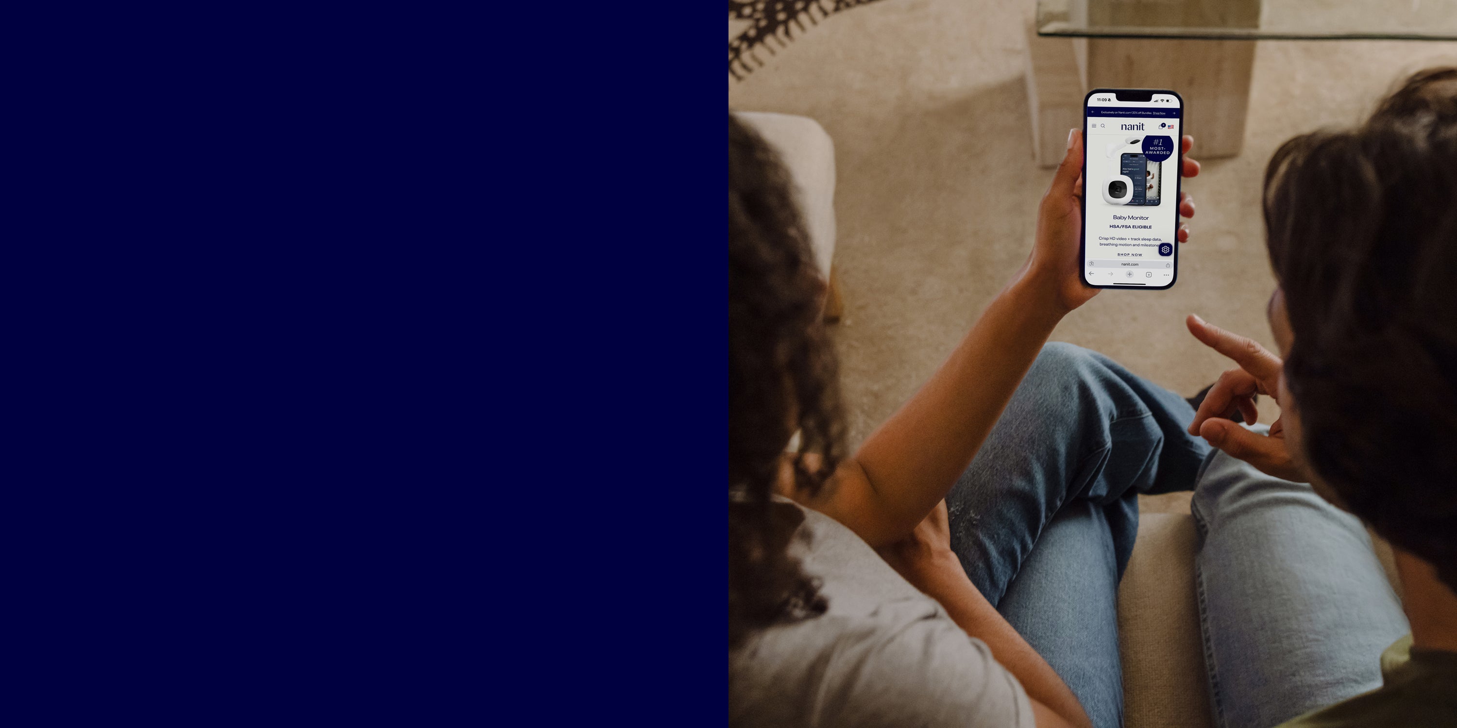 Two people sitting on a couch, looking at a smartphone displaying an app.