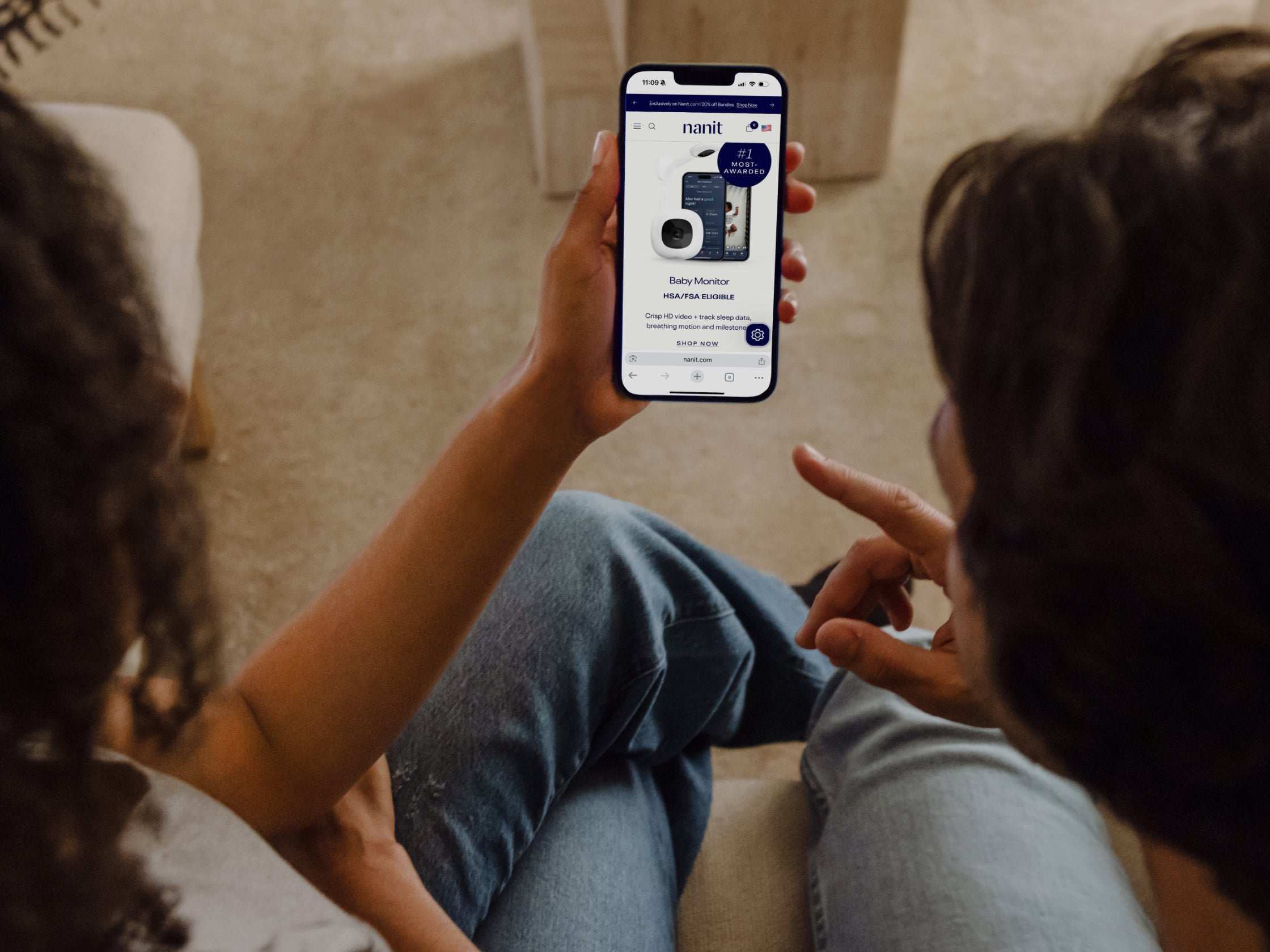 Two people sitting together, looking at a smartphone displaying a website.