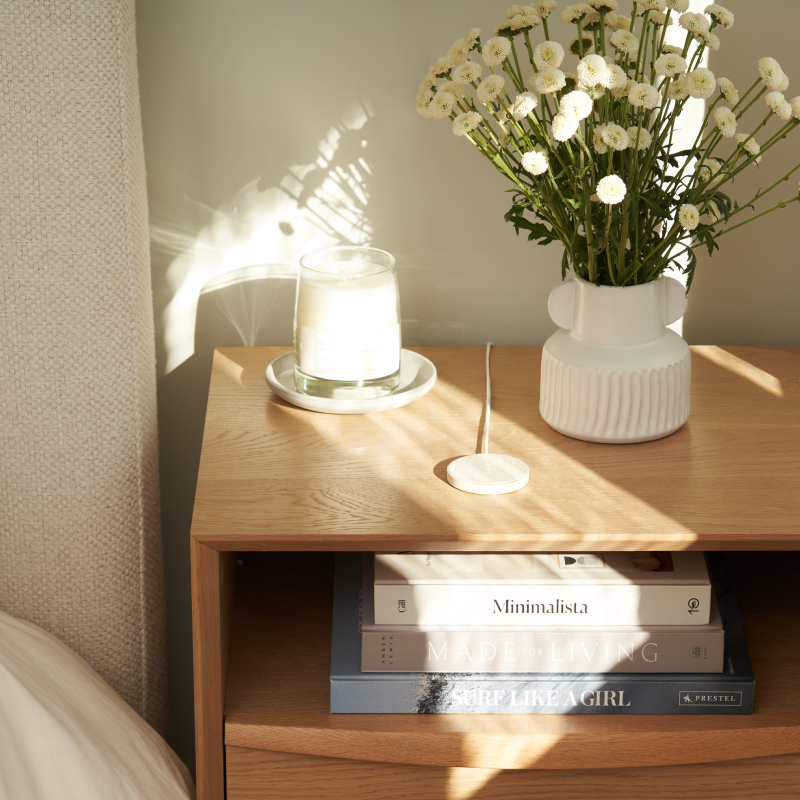 courant mag:1 essentials charger on bedside table in between candle and plants
