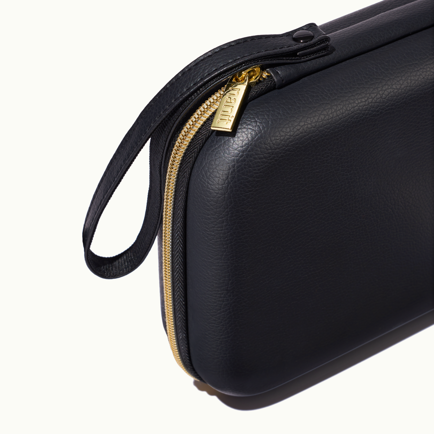 zoomed in picture of gold zipper and strap on black travel case #color_black