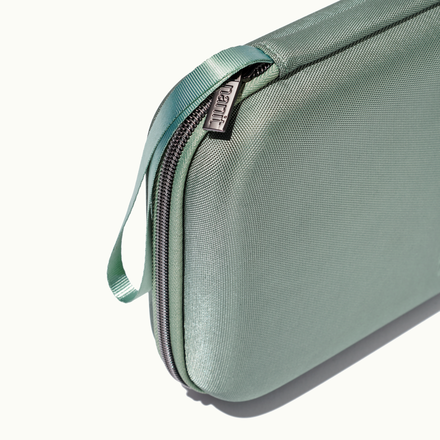 zoomed in picture of gray zipper and strap on green travel case #color_green