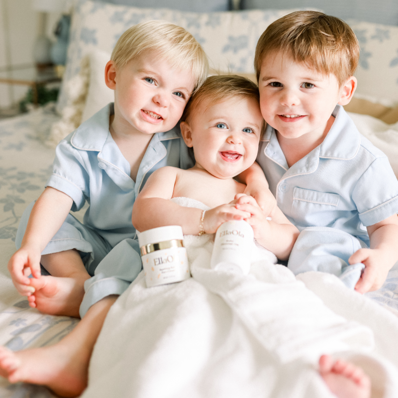 Three babies in bed with EllaOla products