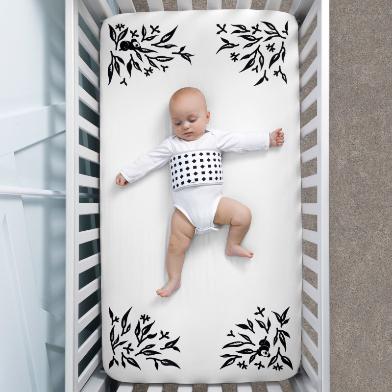 baby wearing breathing band laying on crib with white smart sheet covered #color_white