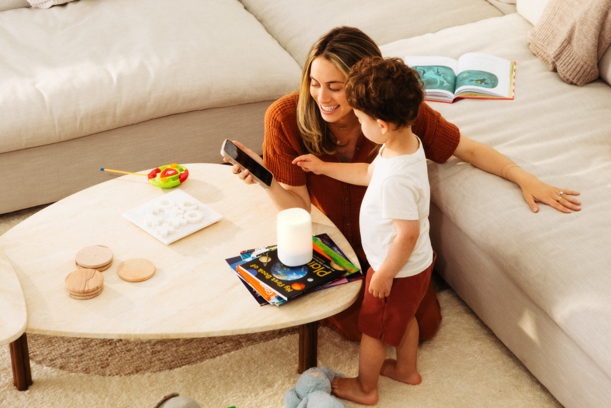 Woman playing with Toddler on floor with crib and nanit pro wall mount in background 