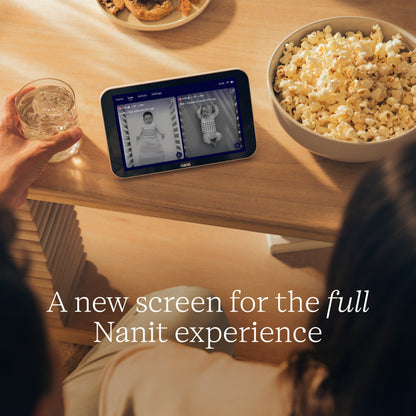 Person using Nanit Home on a table with popcorn and water, text overlay 'A new screen for the full Nanit experience'.