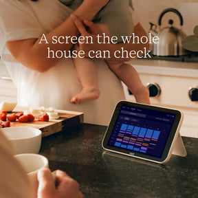 Nanit Home on a kitchen counter with text 'A screen the whole house can check' above.
