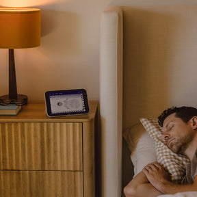 Man sleeping in bed with Nanit Home on the nightstand.
