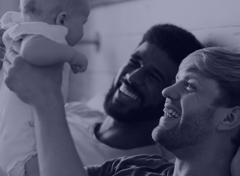 two smiling dads with raising baby