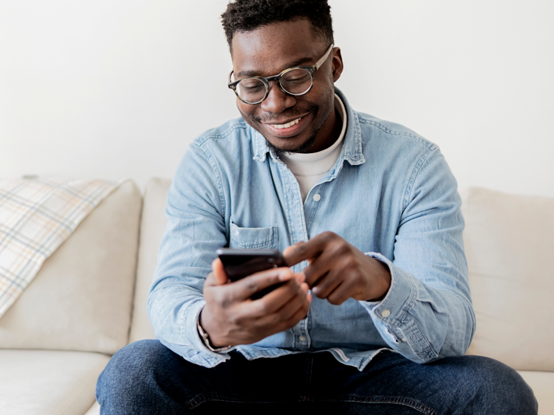 man looking at phone while sitting on couch