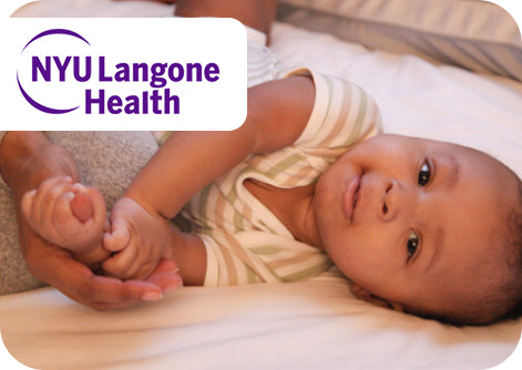 Baby lying on a white blanket with NYU Langone Health logo in the corner.
