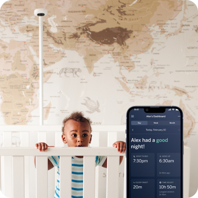 child  over looking over crib with nanit Pro camera wall mount in background and mobile display in front