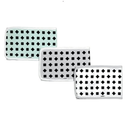 Three folded rectangular cloths with black geometric patterns—squares and diamonds—on white or light mint backgrounds, each bordered with white trim, arranged in a staggered row 