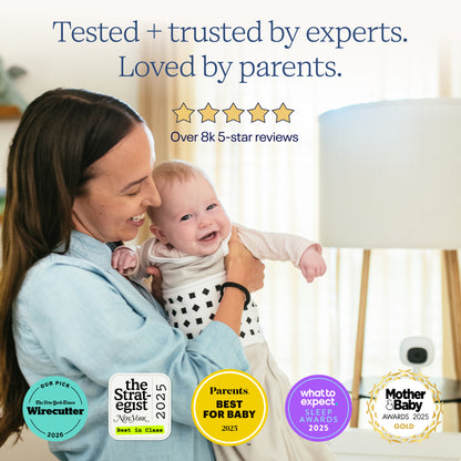 Woman holding a baby with product awards displayed on a blurred background