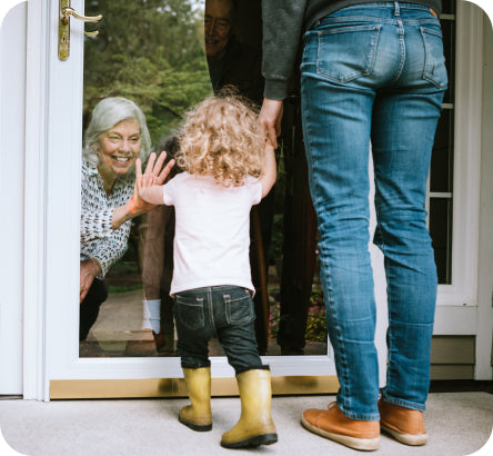 Grandma greeting toddler at the door with mom