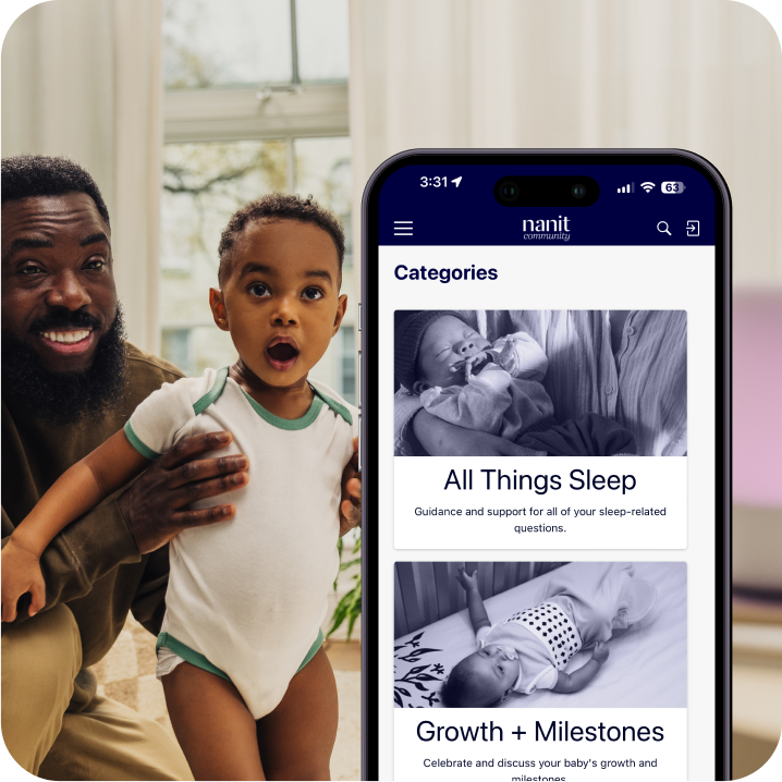 Dad holding baby from behind while baby is standing - baby wearing nanit sleep wear short sleeve bodysuit in spruce green