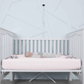 baby sleeping in nanit pajamas in crib covered in pink smart sheet with nanit pro and clearance floor stand in front of crib #color_pink