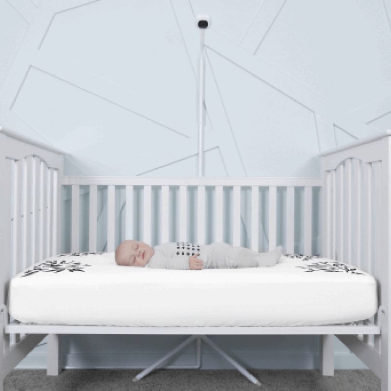 baby sleeping in nanit pajamas in crib covered in white smart sheet with nanit pro and clearance floor stand in front of crib #color_white