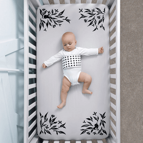 baby wearing breathing band laying on crib with gray smart sheet covered #color_gray