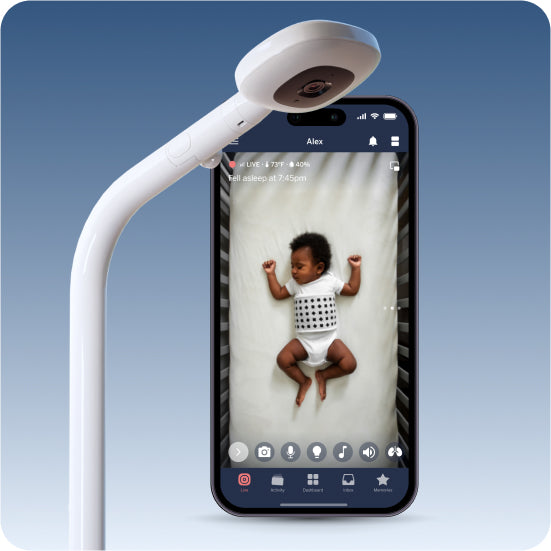 Smartphone with a baby monitor app displaying a child on the screen, with a white baby monitor attached above.