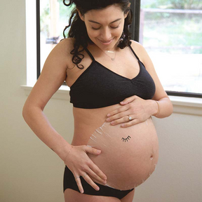Pregnant woman showing sheet mask on belly