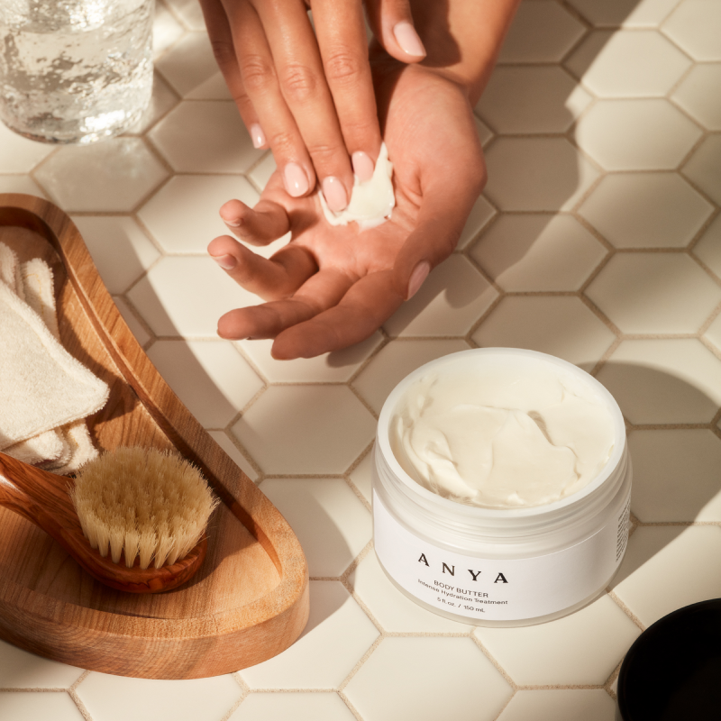 anya body butter lotion opened and applied on hands in bathroom setting
