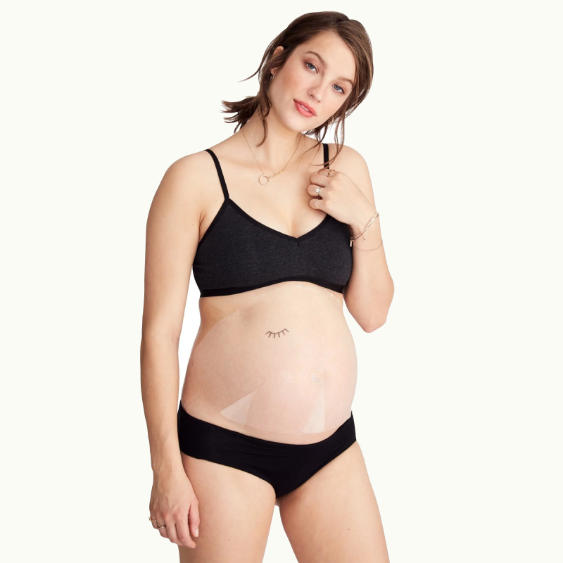 Pregnant woman showing sheet mask on belly