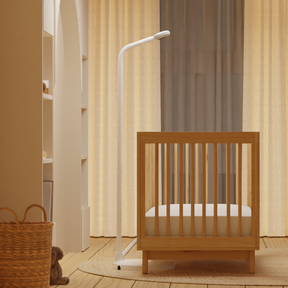 side view of nanit pro camera + floor stand in front of low crib where floor stand fits 